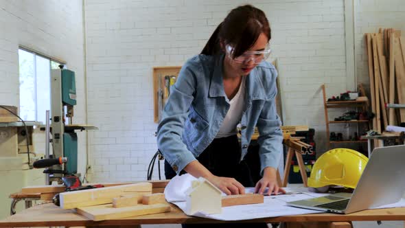 Carpenter student searching wood construction project in laptop on workshop table in workshop