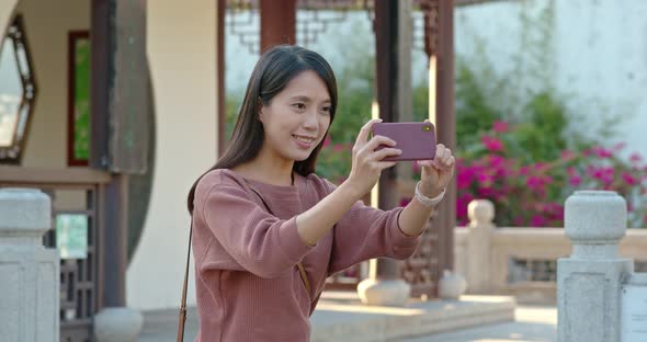 Woman take photo on cellphone in chinese garden alt