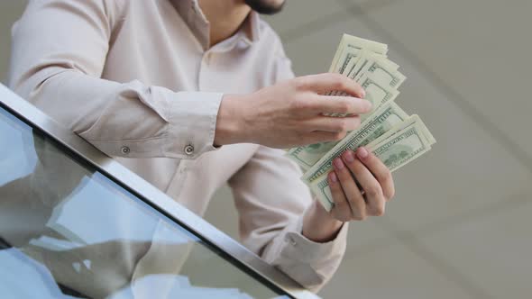 Closeup of Male Hands Counting Dollar Bills Outdoors alt
