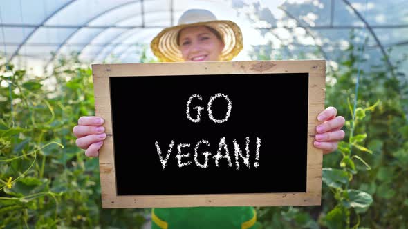 Smiling woman with a sign in her hands calls for healthy food. Vegetarianism, vegan alt
