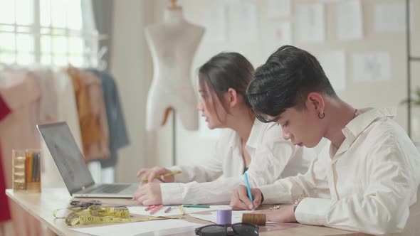 Two Fashion Designers Working With Laptop And Sketching At Fashion Design Studio alt