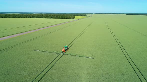 The Protection Of Plants.Tractor Spraying A Green Wheat Field alt