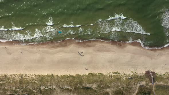 AERIAL: Top View Shot of Isolated Surfer with Wind Kite Standing on Beach with Rippling Waves