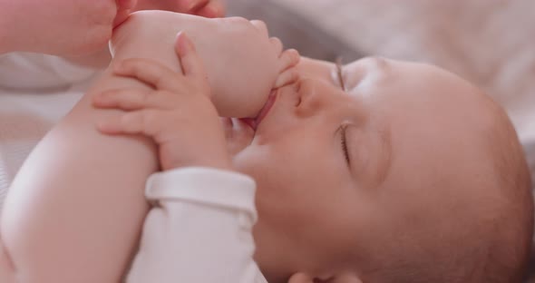 Close Up Adorable Sleeping Baby Who Sucks the Finger on Feet While Sleeping Naked in Diapers in Bed alt