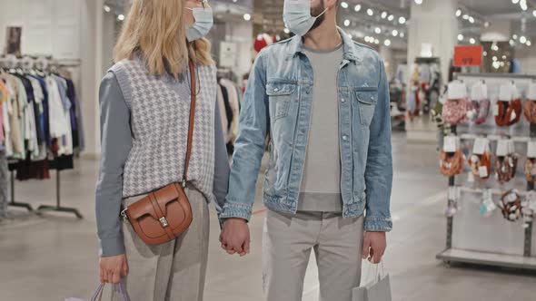Portrait Of Stylish Couple In Face Masks in Clothing Store alt