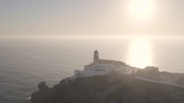 Cinematic aerial tracking shot of cape Saint Vincent lighthouse with sun setting alt