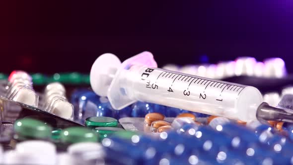 Usual Syringe Lays on Different Pills, Rotation, Reflection, Close Up, on Black, Back Light Red and alt