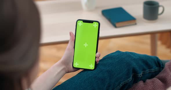 Backside View of Deaf Person Holding and Looking at Smartphone Green Screen. Woman Using Sign alt