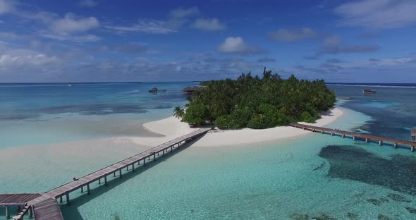 Aerial view of luxury Maldives island with white sand and over water villas and palm trees