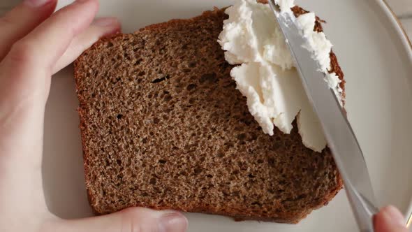 Butter Knife Rubs Cottage Cheese on Piece of Bread
