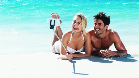 Couple lying on beach and taking a selfi from mobile phone alt