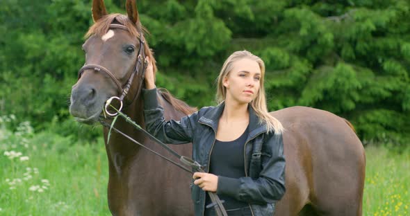 Young Woman Caressing Her Arabian Horse Standing in the Field alt
