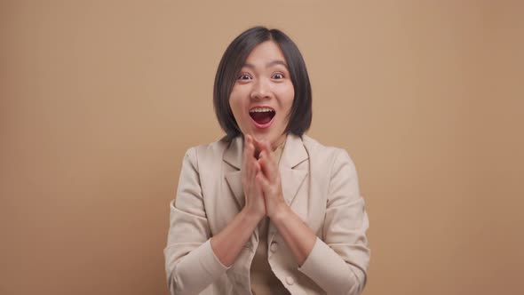 Asian business woman happy smiling and excited looking at camera isolated over beige background.