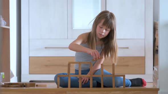 Happy Child Girl Playing Game Stacking Wooden Toy Blocks in High Pile Structure alt