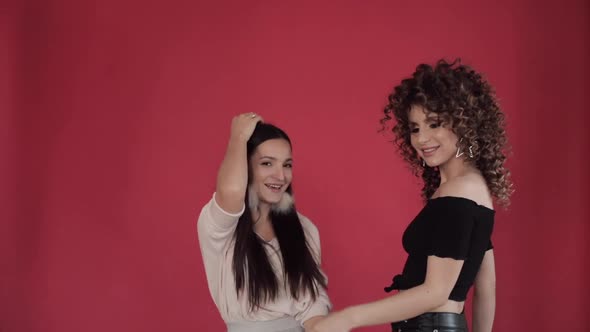 Two Happy Friends Dancing and Singing Against Red Background in Studio