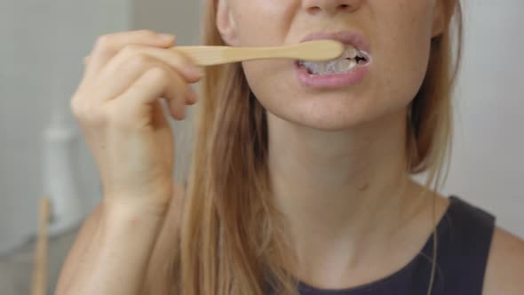 A Young Woman Brushes Her Teeth with a Brush Made of Bamboo Wood alt