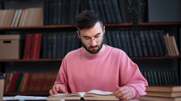 Confident Smart Hispanic Man Reading Vintage Paper Book Turning Pages at Public Library Desk alt