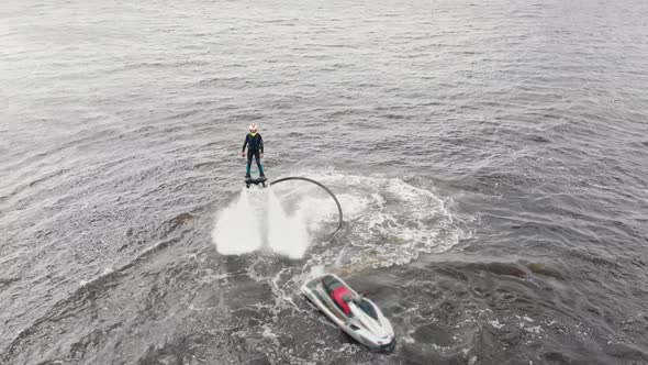 Water Sports  a Man Flying Around Over the Water with a Jet Ski Nearby  Aerial View alt