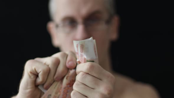 a Man Tears Five Thousandth Russian Rubles on a Black Background