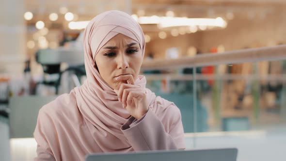 Young Pensive Puzzled Arab Woman in Hijab Working on Laptop Concentrating on Idea Looking for alt