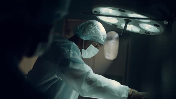 Focused Surgeon Performing Operation in Dark Sterile Hospital Operating Room alt