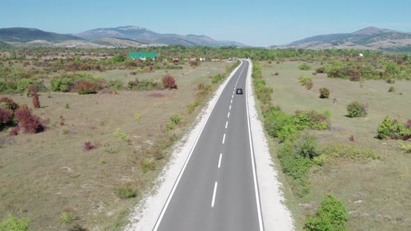 Empty Asphalt Road on the Plateau Between Green Fields Highland Way Aerial View alt