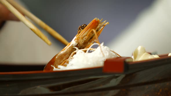 Hand with Chopsticks Taking Shrimp. alt
