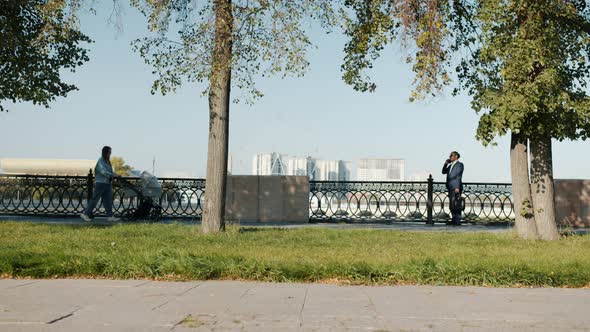 Diverse Group of Men and Women Moving Along Sunlit Street on Summer Day alt
