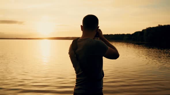 Photographer silhouette at sunrise. Beautiful summer sunset by the river alt