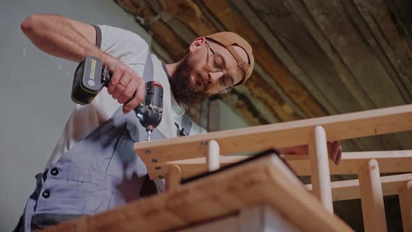 Builder Using Electrical Screwdriver to Create a Wooden Construction in Studio