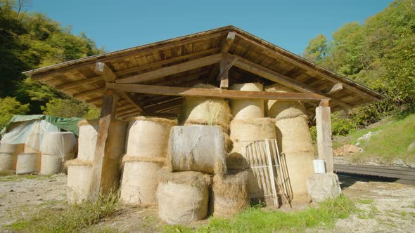 Hay Bales in Plastic Wrap Stacked Under Wooden Canopy