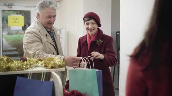 Portrait of Happy Senior Caucasian Couple Buying Presents on Christmas Sales. Smiling Man and Woman alt