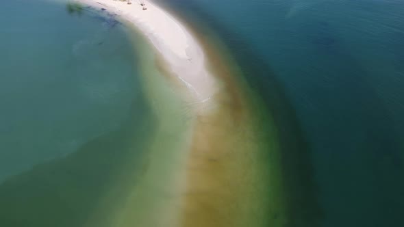 Sandy beach jutting out into the middle of the sea with beautiful water. alt