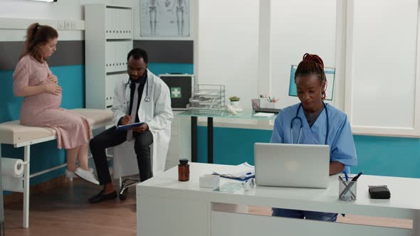 Medical Assistant Working on Laptop in Cabinet at Appointment alt