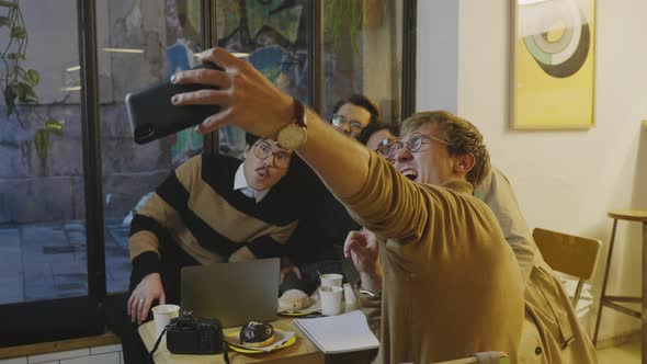 Businessmen Taking Selfie on Smartphone. Friends Making Grimaces on Phone Camera alt