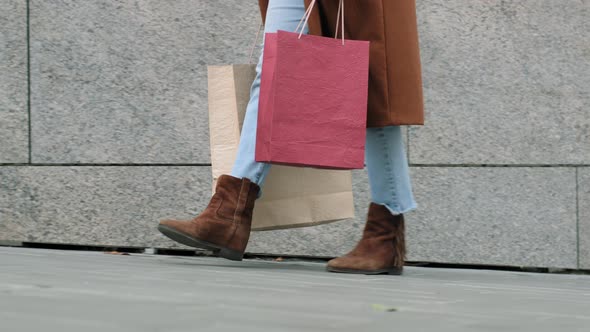 Closeup Female Legs in Jeans Brown Shoes and Coat Walking Along Sidewalk in City on Street alt