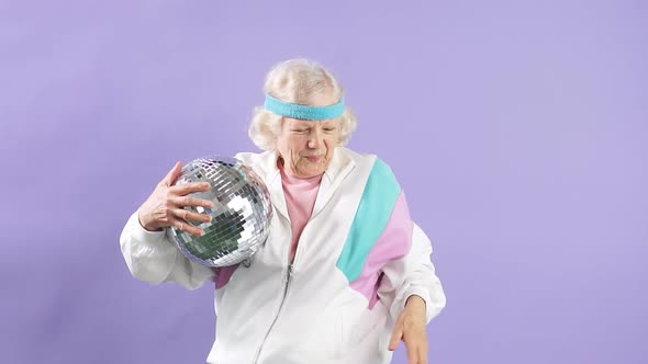 Positive Elderly Lady Holds Sparkling Disco Ball Smiling at Camera alt