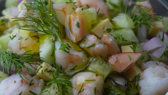 Chef pouring olive oil in delicious shrimp salad of cucumber, cheese and onion alt