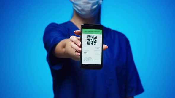 Woman Surgeon in Medical Uniform Showing Vaccination Passport with Qr Code on Phone International alt