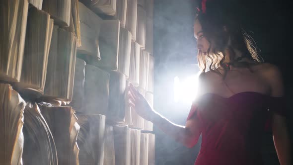 Woman Walks Along Wall with Books and Runs Hand Over Pages alt