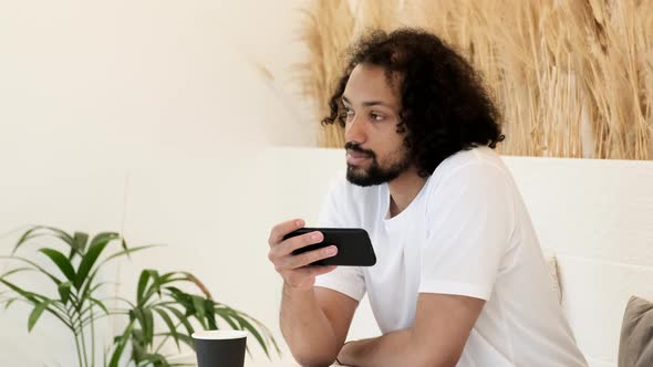 A Young Indian Man Is Working Online On A New Project and Using A Smartphone, Watching Social alt