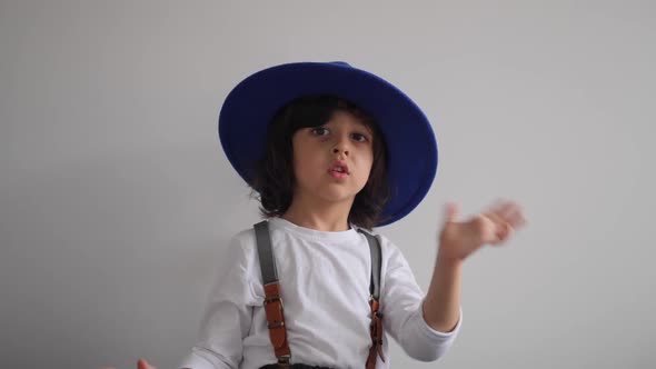 Boy Dances at Home in a Blue Hat with a Brim and a White Tshirt alt