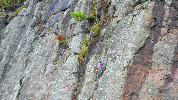 Aerial footage Orbit around young female climber on cliff revealing her instructor.mp4 alt