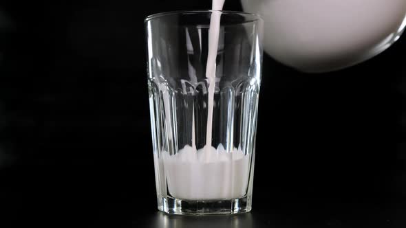 Milk Is Poured Into a Glass Black Background. Close Up