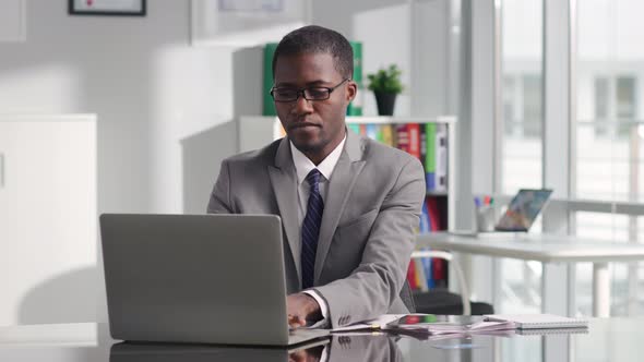 Portrait of Successful AfricanAmerican Politician Working on Laptop in Modern White Workspace alt