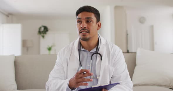 Portrait of happy hispanic male doctor having interview with patient at home alt