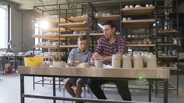 Cute Caucasian Boy with His Father Kneading Clay for Ceramic Pots alt