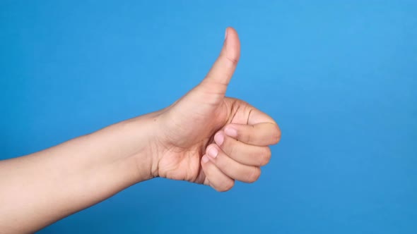 Women's Hand Hand Showing a Thumb-up on Blue Background  alt