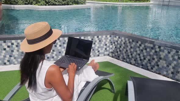 Asian Women with Hat Checking Laptop on Holiday Vacation Digital Nomad Concept alt