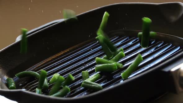 Green French Beans Falling in a Frying Pan on a Kitchen Gas Stove